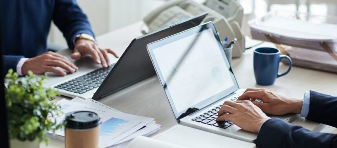 Cropped image of business people working on laptops in office