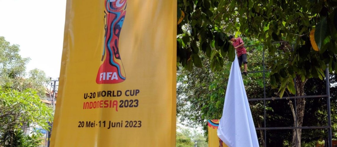 Un trabajador retira una pancarta de la Copa Mundial Sub-20 de la FIFA 2023 en un roan principal en Denpasar, Bali, Indonesia. EFE/EPA/MADE NAGI